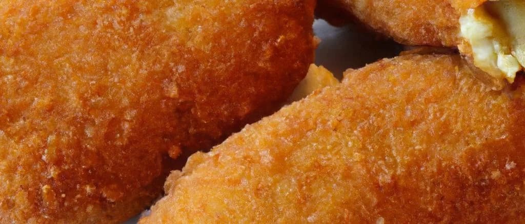 Variety of gourmet kroketten displayed against a rustic wooden background, highlighting their crispy outer texture and diverse filling options.